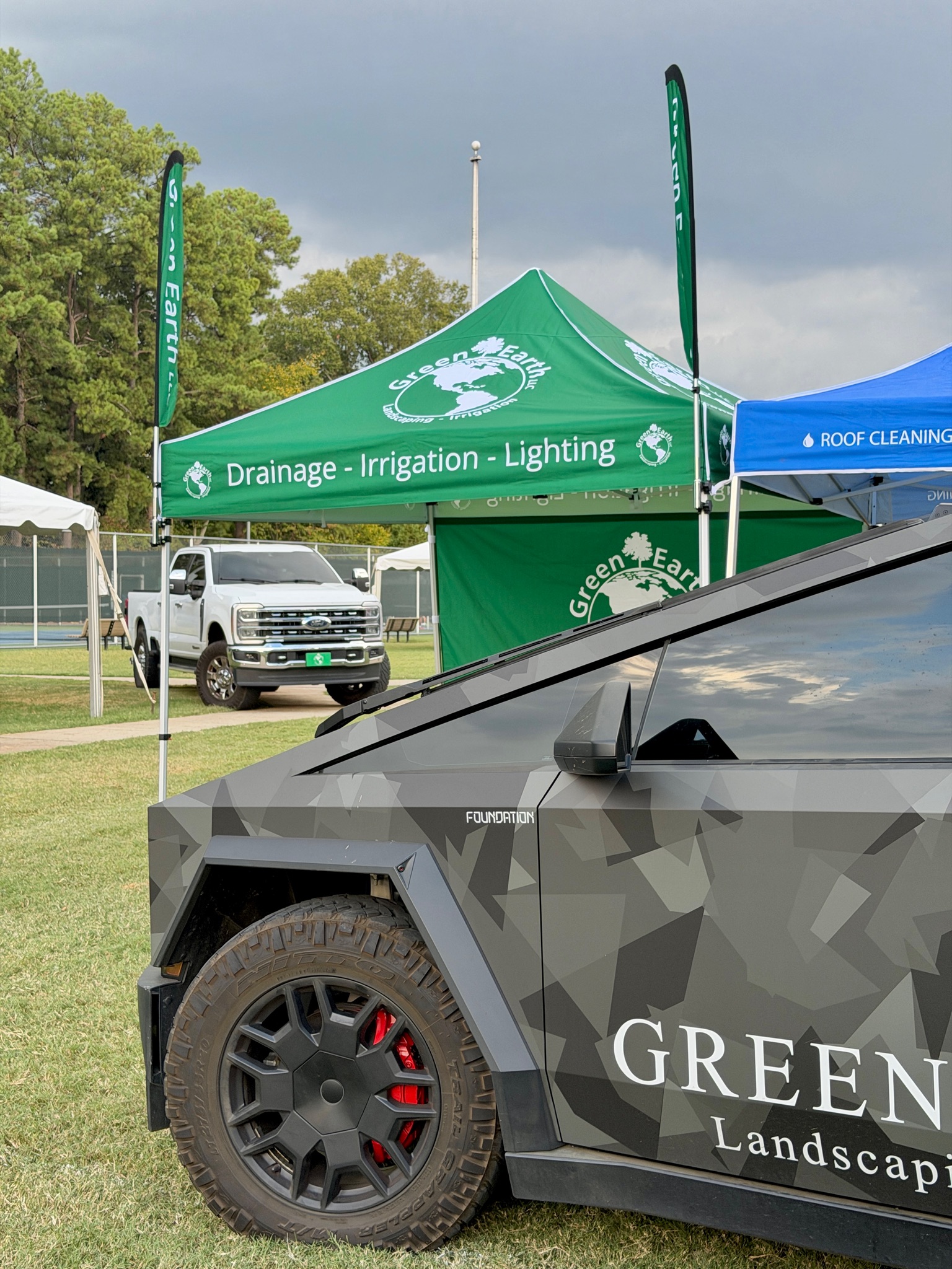 Green Earth Cybertruck wrapped with GREEN EARTH lettering parked beside the Green Earth festival tent