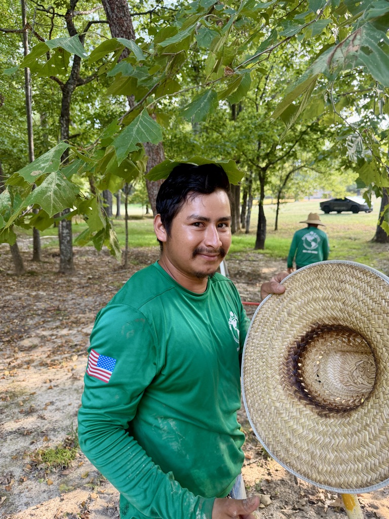 Close-up portrait of a Green Earth crew member with a straw hat nearby