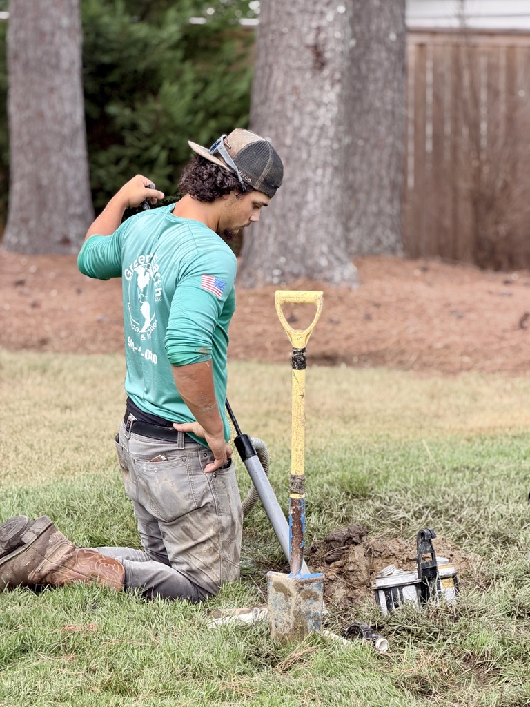 Green Earth crew member kneeling to work on an irrigation valve