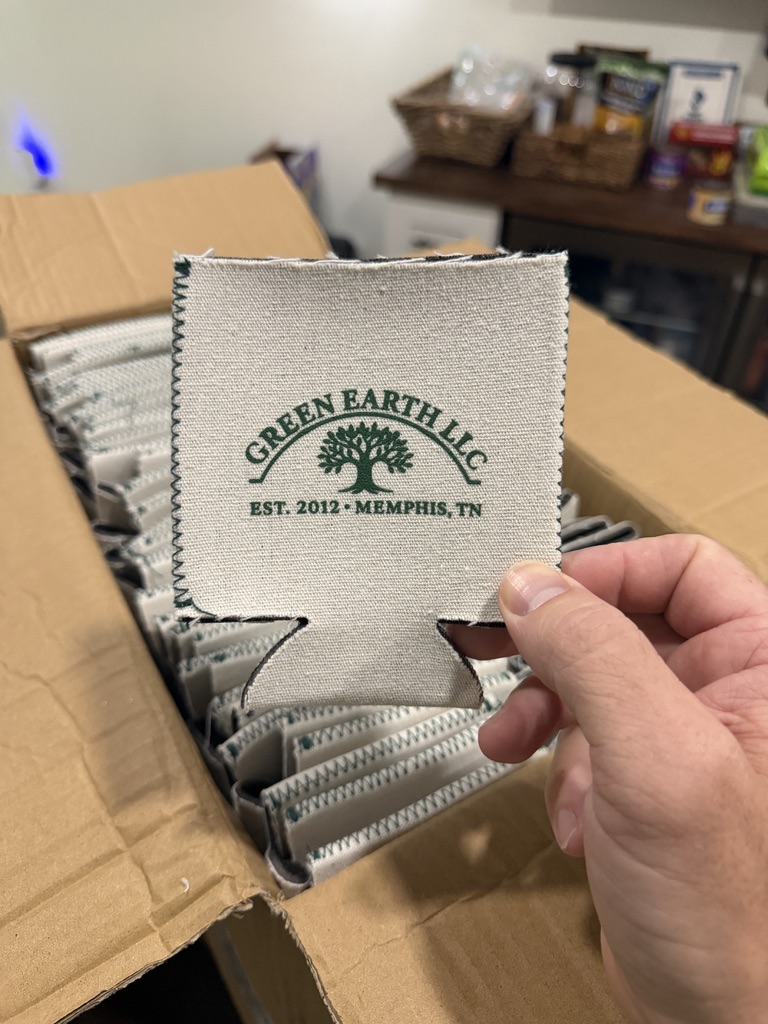 Hand holding a stack of Green Earth LLC embroidered logo patches