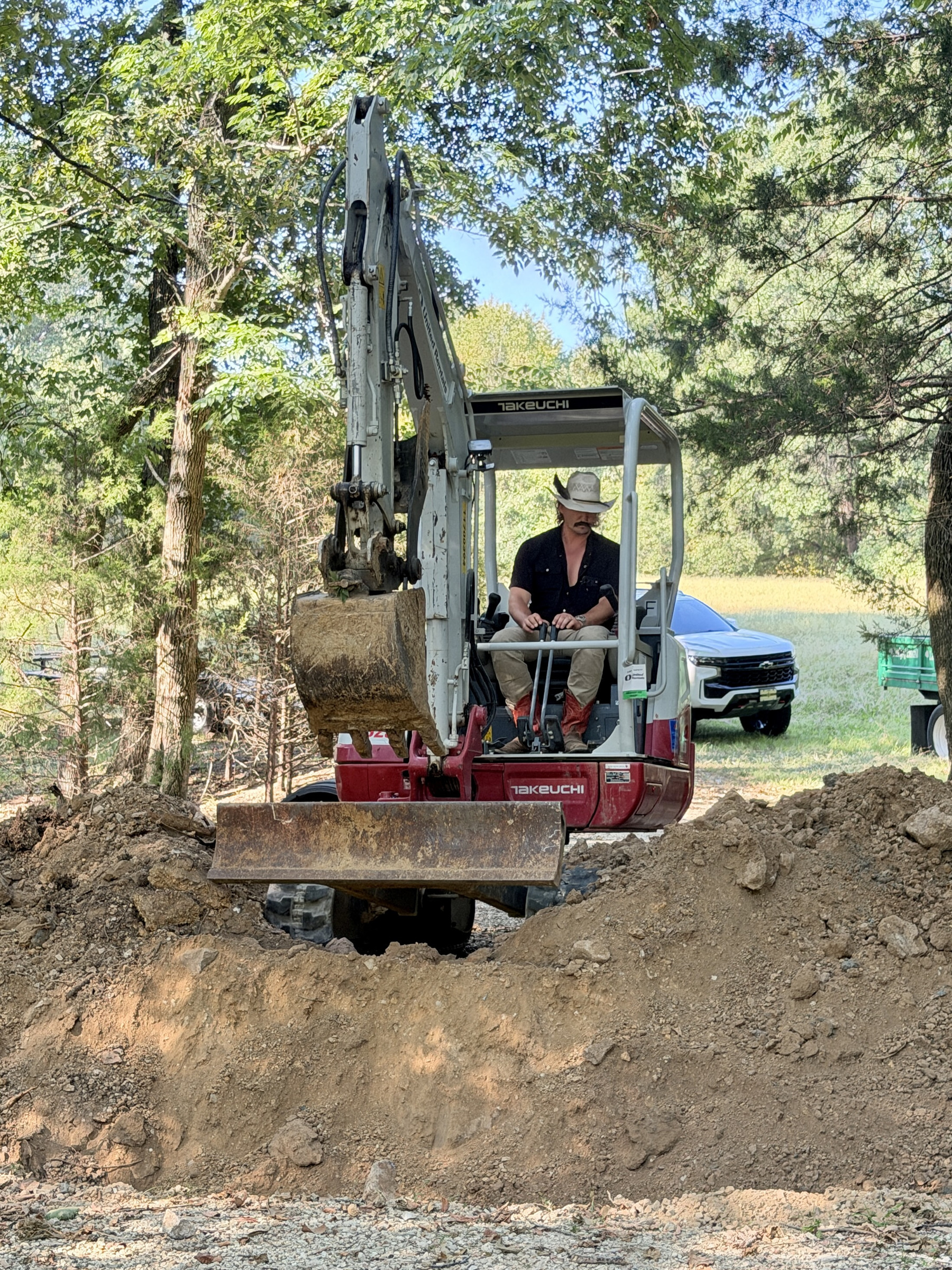 Green Earth crew member operating a yellow mini excavator